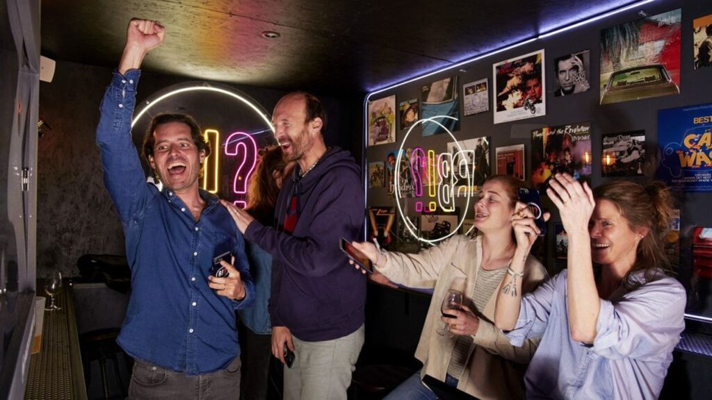 Groupe d'amis célébrant dans un bar illuminé.