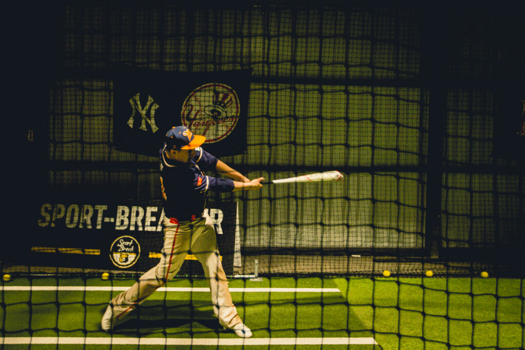 Joueur de baseball frappant dans une cage intérieure.
