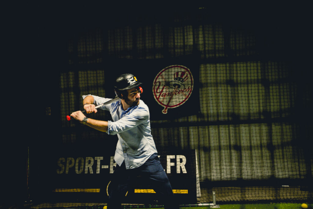 Homme jouant au baseball en intérieur, casqué.