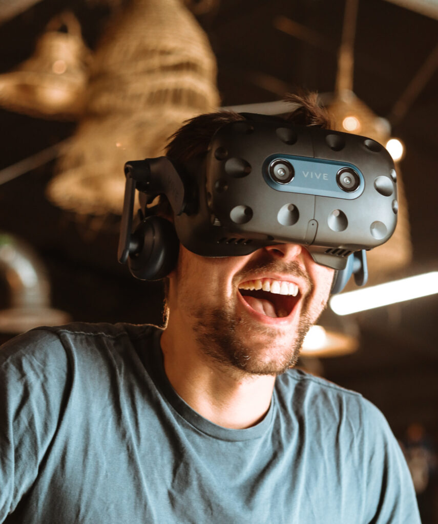 Homme souriant utilisant un casque de réalité virtuelle.