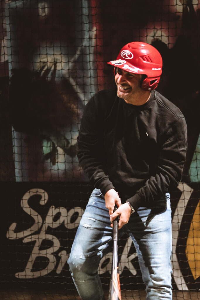 Homme souriant jouant au baseball en intérieur.