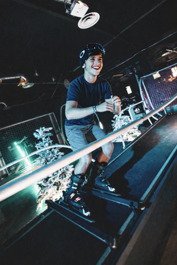 Jeune homme souriant pratique le ski intérieur.