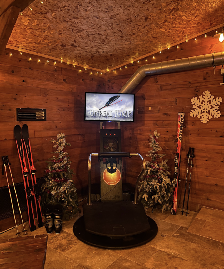 Salle de sports d'hiver intérieure avec écran et skis.