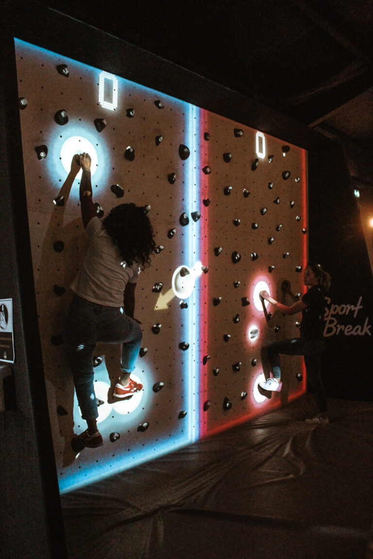 Deux personnes escaladant mur interactif en salle.