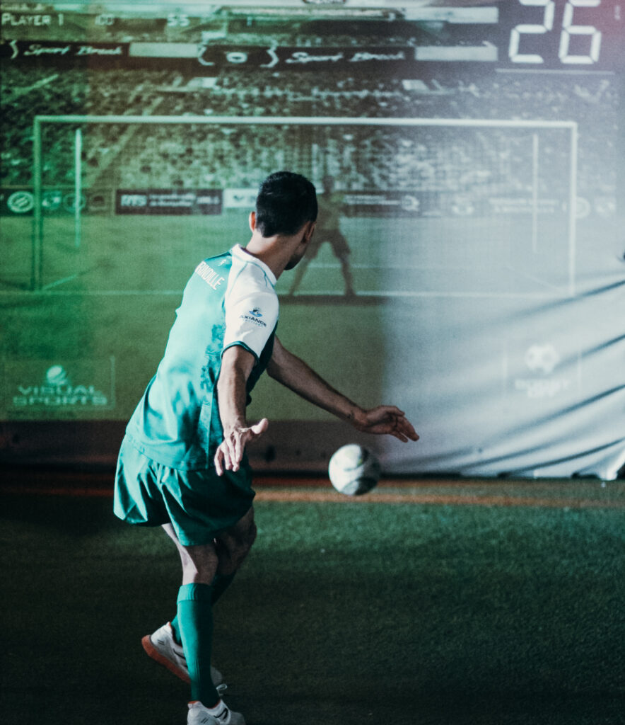 Joueur de football frappant un ballon sur terrain.