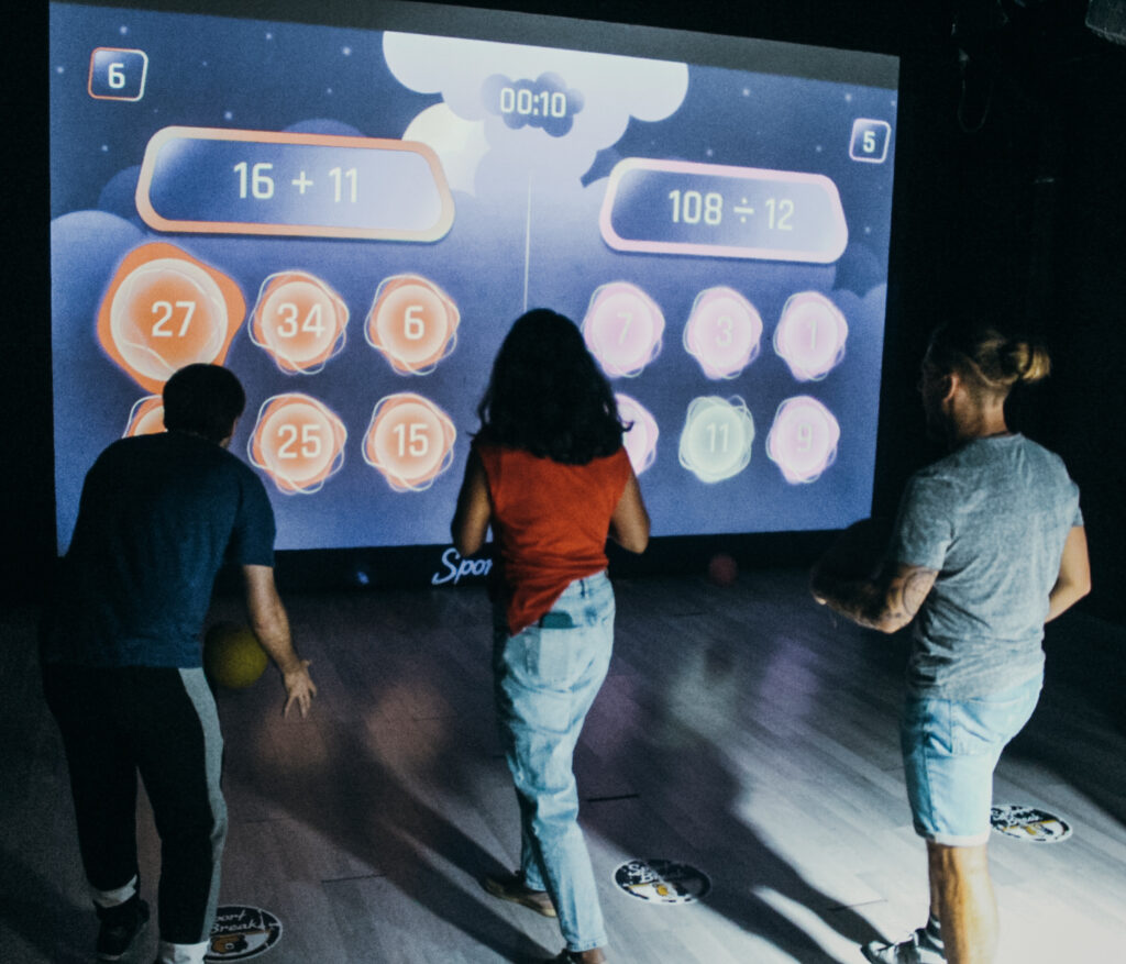 Personnes jouent à un jeu interactif sur écran.