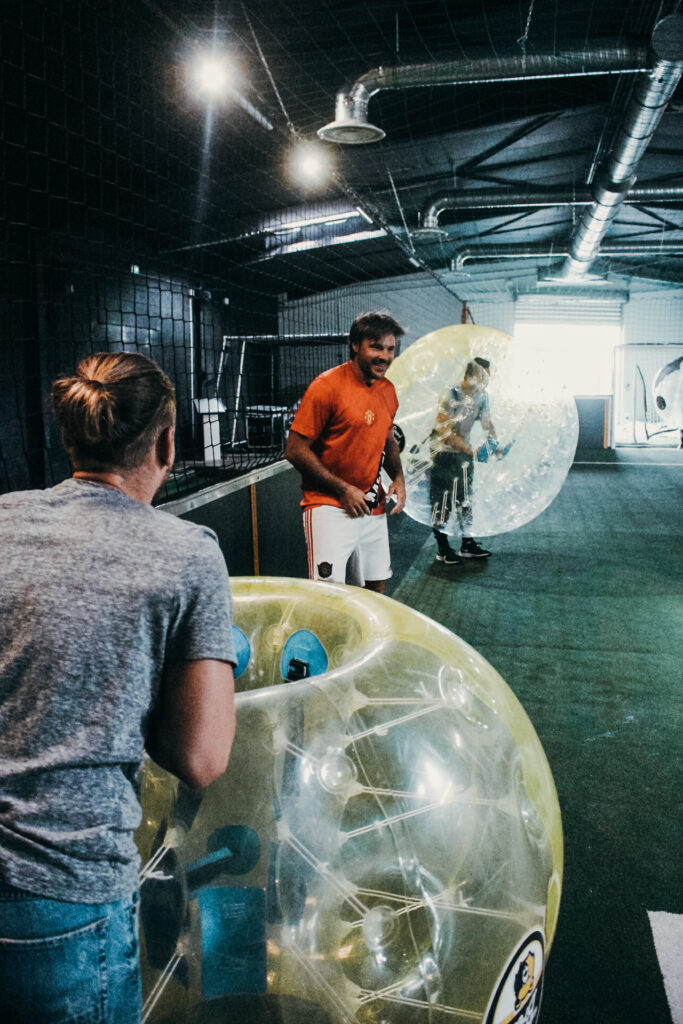 Personnes jouant au bubble foot en intérieur.