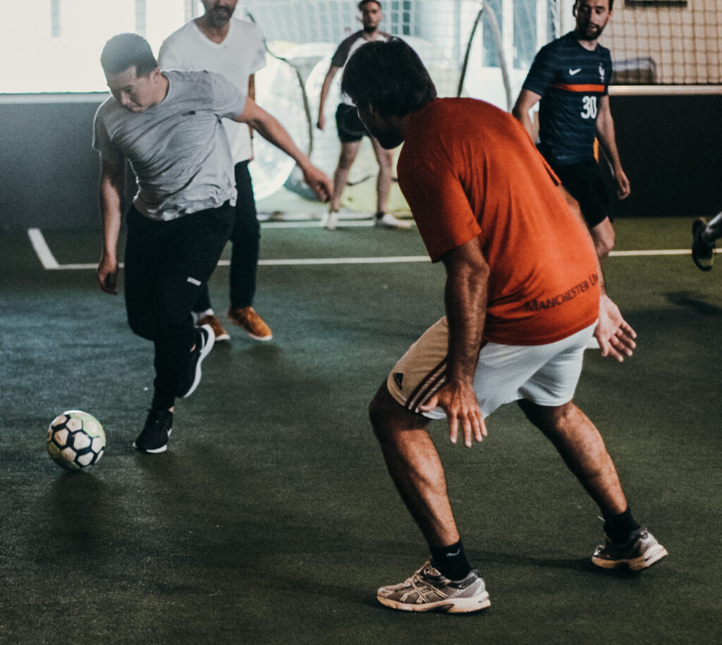 Des hommes jouent au football en salle.