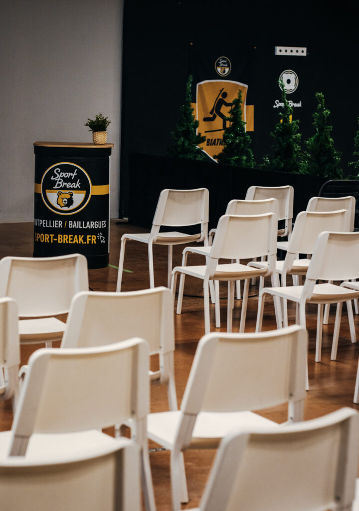 Salle de conférence avec podium et chaises vides.
