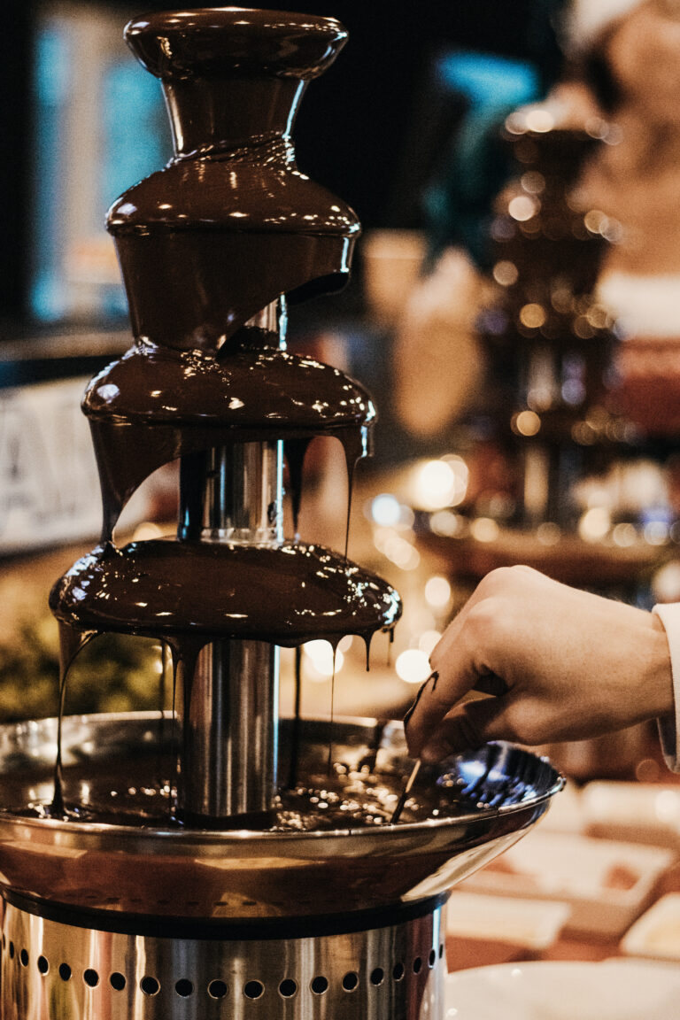 Fontaine à chocolat avec main tenant une fourchette.