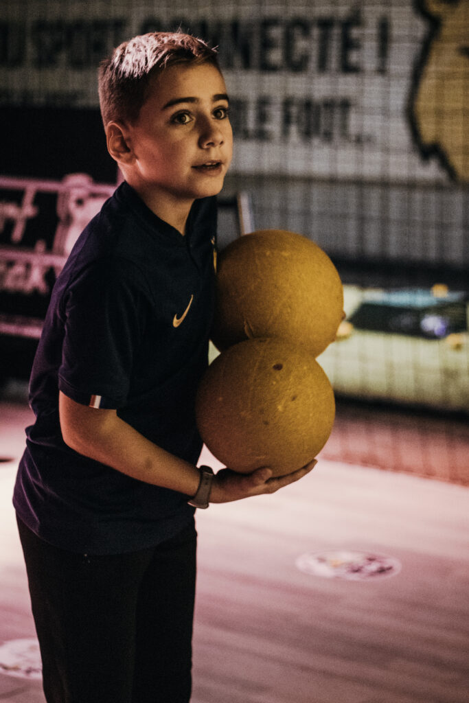 Enfant tenant ballons jaunes dans une salle de sport.