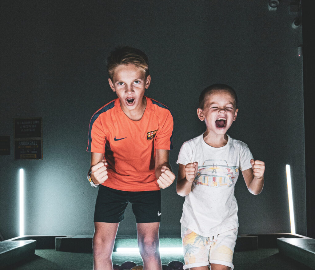 Deux enfants jouent au snookball, enthousiastes et concentrés.