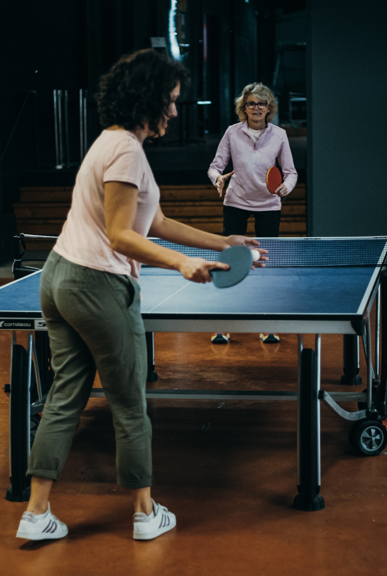 Deux femmes jouent au tennis de table.